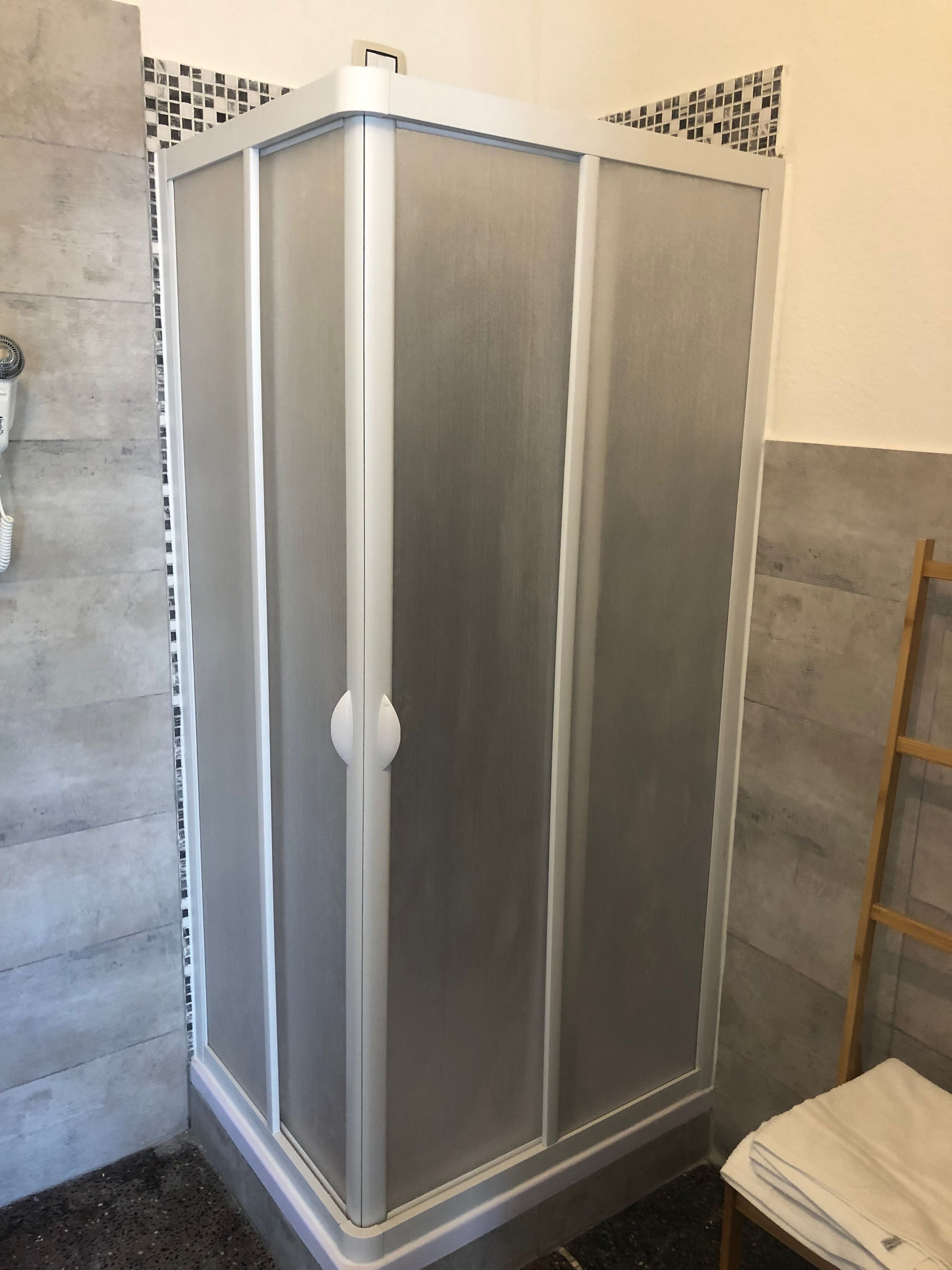 Un baño con cabina de ducha, paredes azulejadas y una escalera de madera.