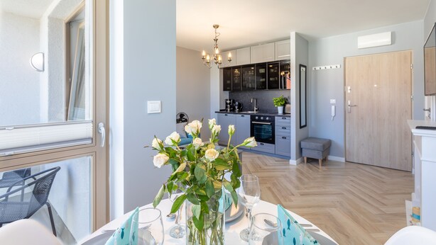 Een moderne keuken met donkere kasten, een centraal eiland en een kroonluchter.