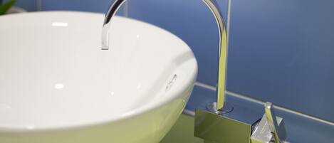 A white ceramic sink with a chrome faucet mounted on a green tile backsplash.