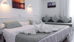A modern hotel room with a neatly made bed, a sofa, and two wall-mounted lights. -  Hostal Bellavista Formentera (Formentera)