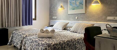Une chambre d’hôtel avec un lit, deux lampes de chevet, un tableau au mur et un bureau avec une chaise.