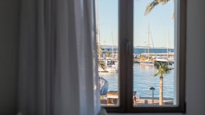 A view from a window overlooking a marina with boats and a palm tree. -  Hostal Bellavista Formentera (Formentera)