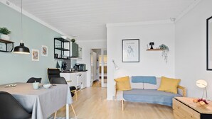 Moderni, avoimen pohjaratkaisun mukainen olohuone, jossa on ruokailutila, pieni keittiö ja oleskelualue.