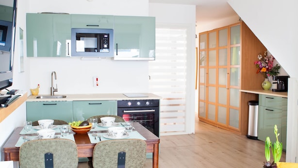 Een moderne keuken met een eethoek, een rode bank en een klein bijzettafeltje met een plant.