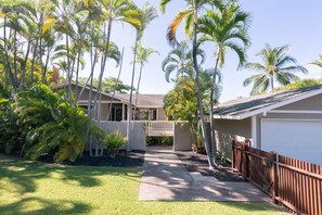 A residential property with a covered patio, palm trees, and a white garage.