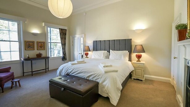 A bedroom with a large bed, bedside lamps, a nightstand, a window with curtains, a desk, and a chair. - Luxurious Georgian Central Apartment -Parking - 1 (York)