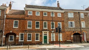 A row of red brick townhouses with white window frames, a green door, and a traffic light in the foreground. - Luxurious Georgian Central Apartment -Parking - 1 (York)