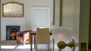 A room with a fireplace, a leather armchair, a dining table, and a door with a brass doorknob. - Luxurious Georgian Central Apartment -Parking - 1 (York)