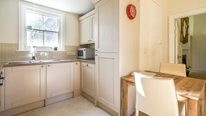 A kitchen with white cabinets, a microwave, a sink, and a dining table with chairs. - Luxurious Georgian Central Apartment -Parking - 1 (York)