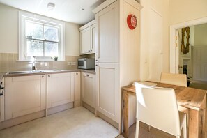 Enjoy meals in this cozy kitchen with a dining table and chairs, microwave, and natural light from the window.