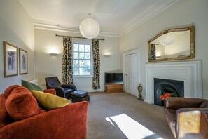 Relax in a classic living room with a comfortable seating area, fireplace, and large mirror.