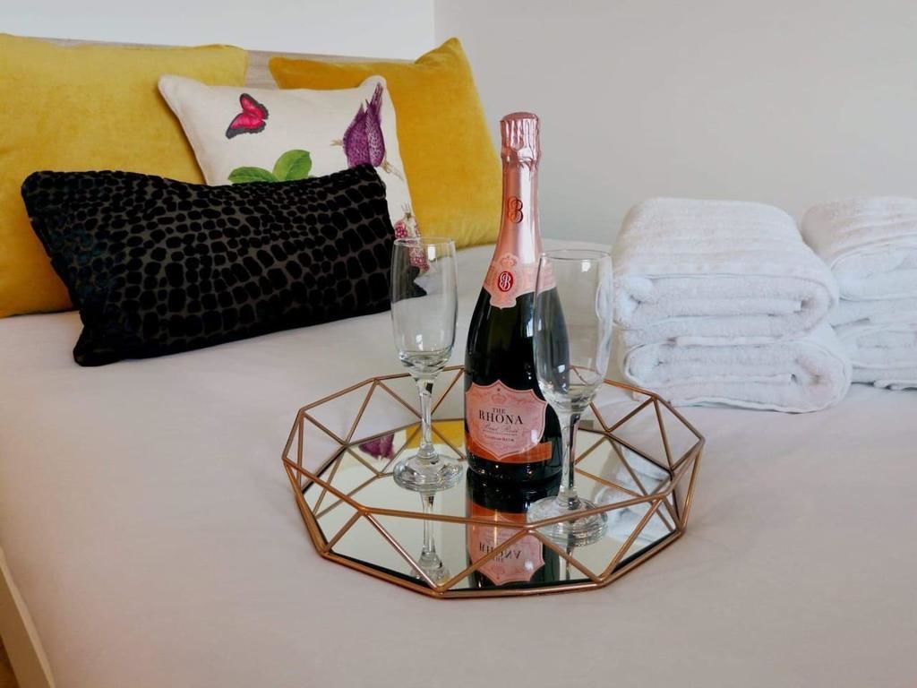 En säng med en flaska champagne, glas och handdukar.