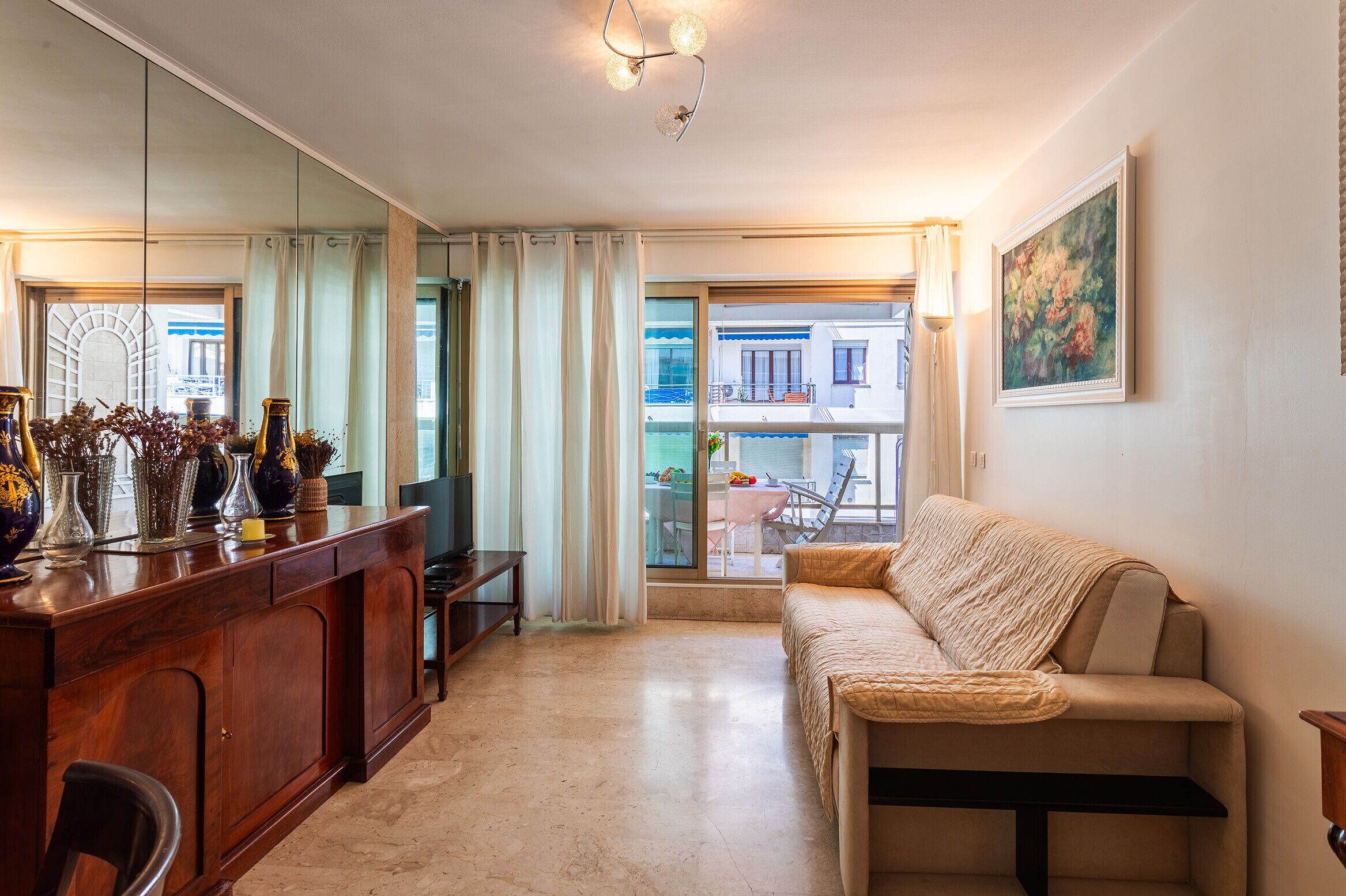 Een moderne woonkamer met een bank, een houten salontafel en een eethoek met een tafel en stoelen. Een groot raam biedt uitzicht op het omliggende landschap.