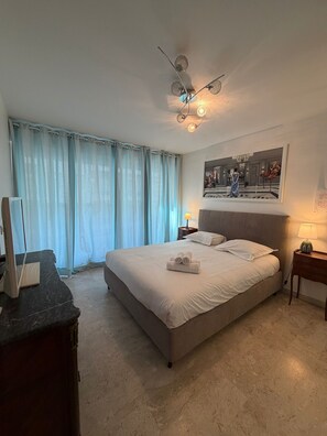 Une chambre d’hôtel avec un lit, un bureau, une lampe et un tableau au mur.