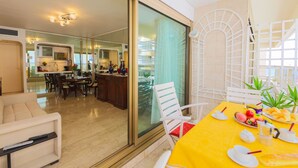 Un salon moderne avec une table à manger jaune dressée pour le petit-déjeuner, un canapé et une cuisine en arrière-plan.