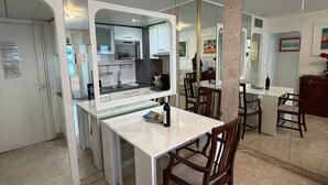 Une cuisine moderne avec des meubles blancs, un îlot central et un coin repas doté de chaises en bois.