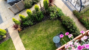 A well-maintained garden with a lawn, a table and chairs, and various shrubs and plants. - Modern Canalside City Townhouse - Parking & Garden (Leeds)