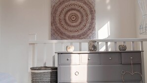 A room with a white dresser, a woven basket, and a wall-mounted circular artwork. - Modern Canalside City Townhouse - Parking & Garden (Leeds)