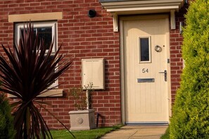 A brick house with a beige front door, a mailbox, and a small potted plant. - Modern Canalside City Townhouse - Parking & Garden (Leeds)