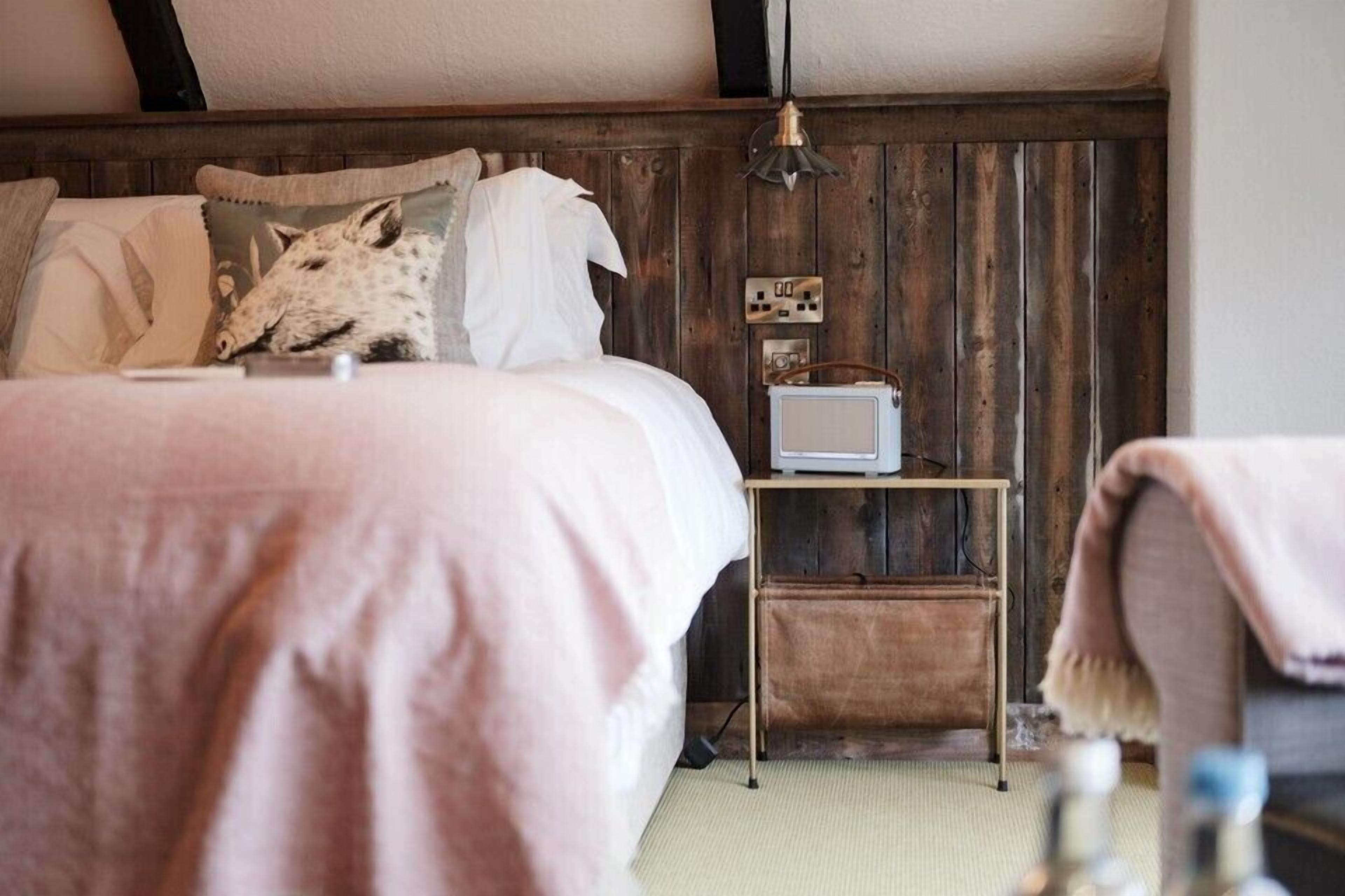Un dormitorio con cama, mesita de noche con televisor y pared de madera.