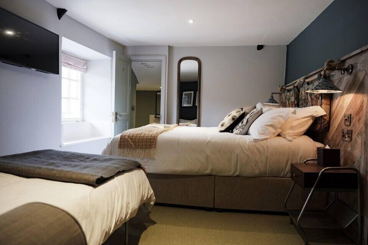 Une chambre avec deux lits, un miroir, des lampes de chevet et un téléviseur.