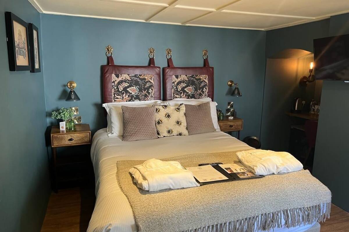Une chambre à coucher bien rangée, avec un grand lit, deux tables de chevet, un téléviseur à écran plat et une lampe fixée au mur.