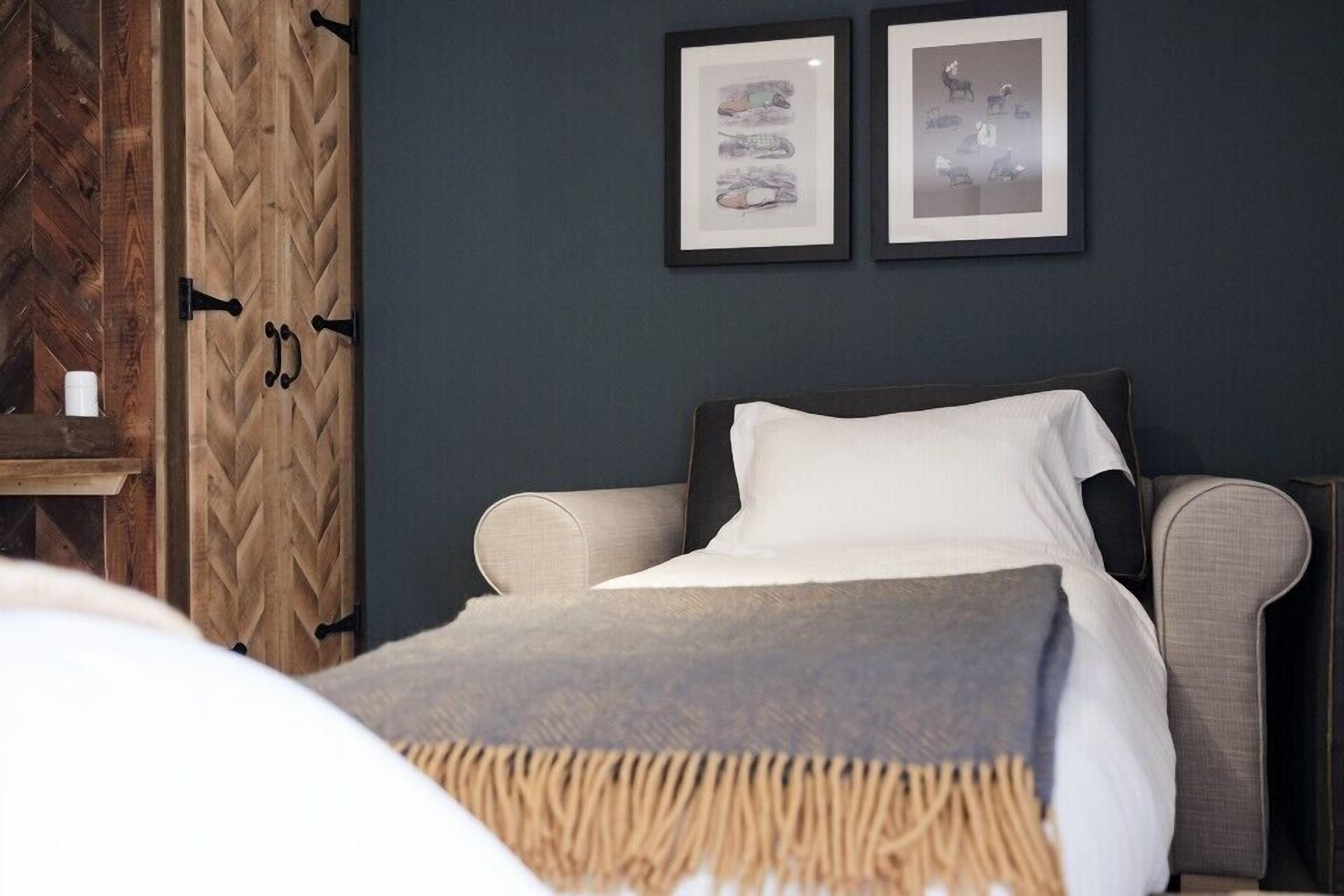 Un dormitorio con cama, mesita de noche y armario de madera. Hay dos cuadros en la pared.