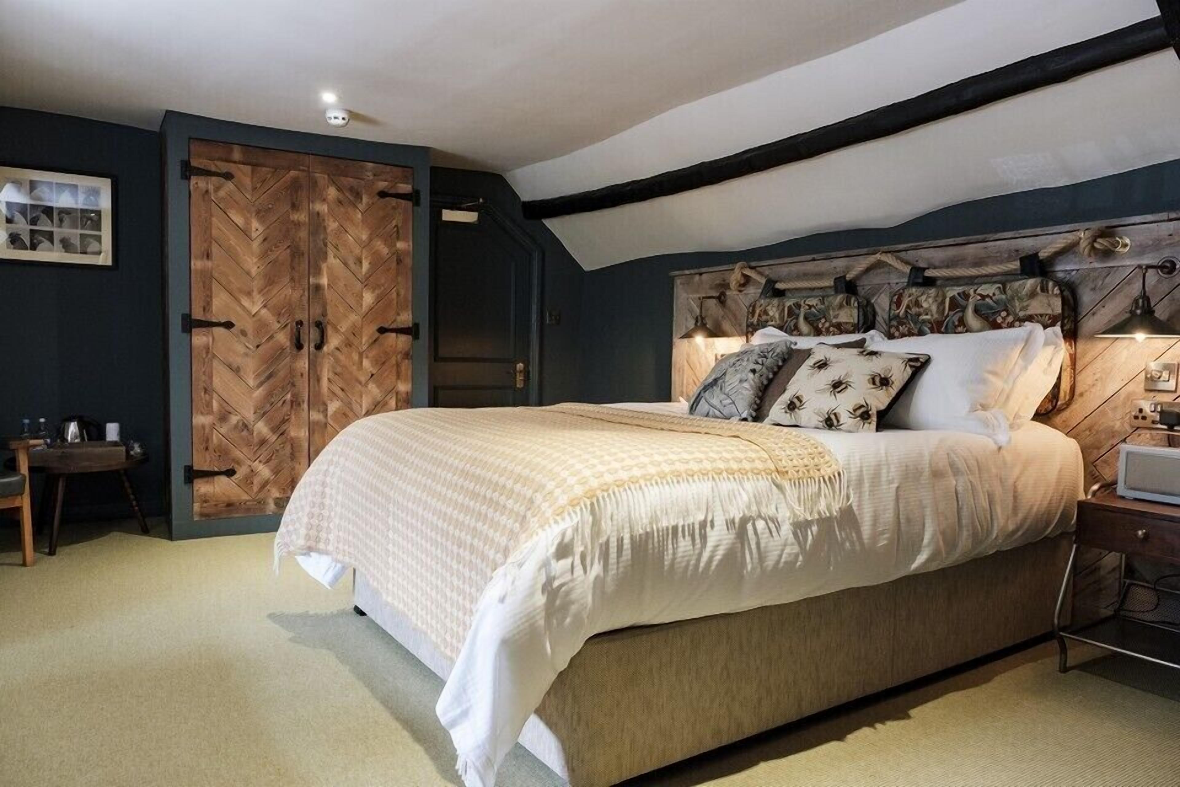 Un dormitorio con una cama grande, un armario de madera y un cabecero con detalles decorativos.