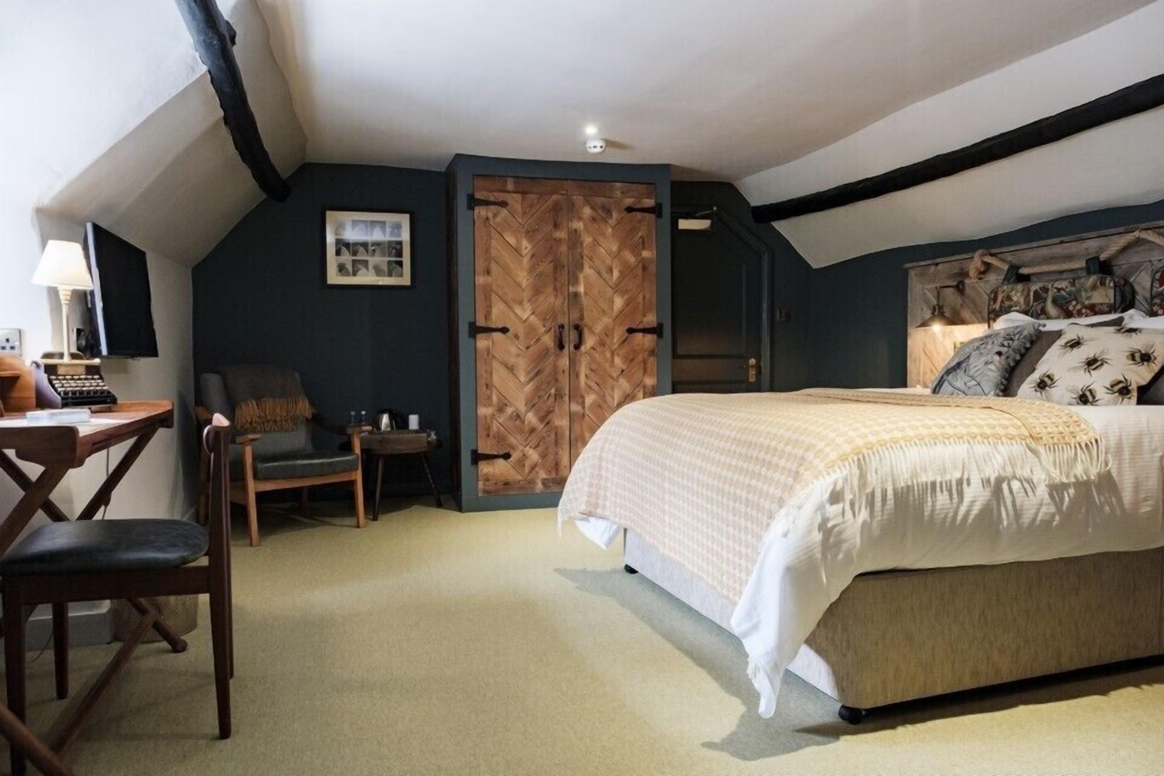 Une chambre à coucher avec un grand lit, un bureau, une chaise et une armoire.