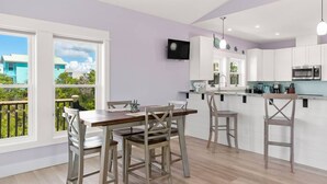 Una cucina moderna con mobili bianchi, un tavolo da pranzo in legno e un balcone con vista sulle case.