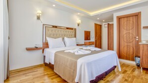 A hotel room with a large bed, wooden headboard, bedside tables, wall-mounted lamps, and a wooden wardrobe. - Violin Boutique Hotel (Istanbul)
