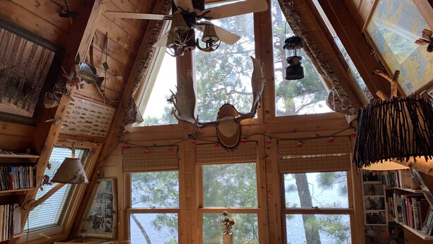 Un chalet confortable avec un plafond en pente, des murs en bois et de grandes fenêtres offrant une vue sur le paysage extérieur.