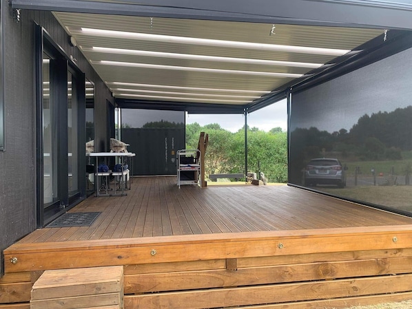 An outdoor deck with a covered area, a table, chairs, and a bench.