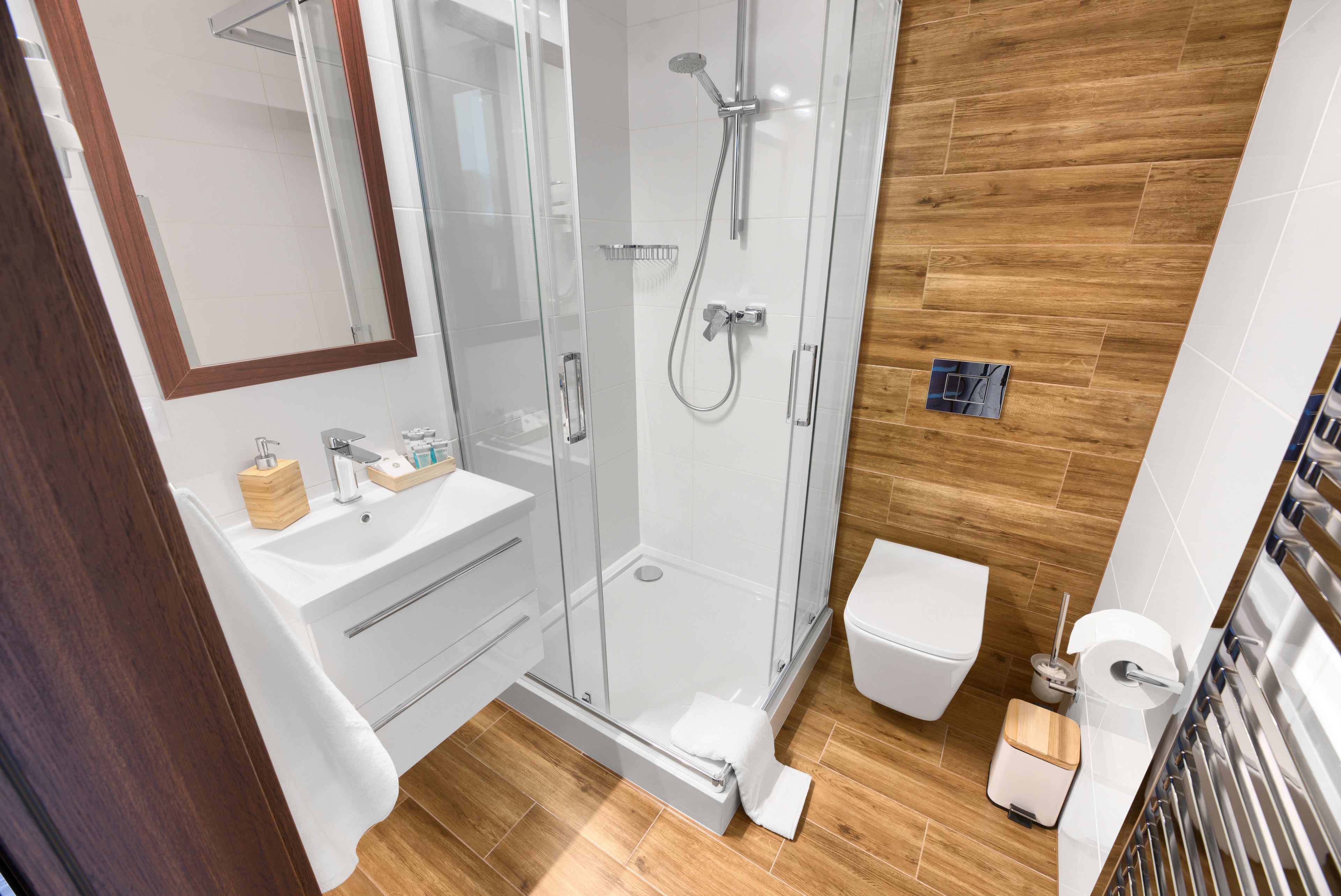 A modern bathroom with a glass-enclosed shower, a white sink, and a toilet.