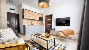 A modern living room with a sofa, coffee table, and a flat-screen TV. - Coffee Inn (Kolbudy)