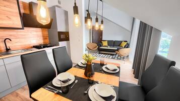 Un comedor moderno con una mesa de madera preparada para cuatro personas, sillas negras y un jarrón central.