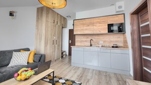 A modern apartment with a grey sofa, a wooden wardrobe, a kitchen with a microwave, and a laptop on a coffee table. - Coffee Inn (Kolbudy)