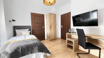 Una camera da letto moderna con un letto, un armadio in legno, una scrivania, una sedia e una televisione.