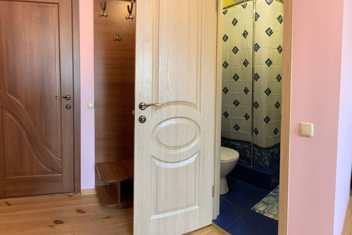A bedroom with a wooden headboard, a bed, a bedside table, a chair, and a window with curtains.