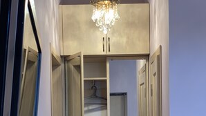 Armadio a muro con ante aperte, un'asta appendiabiti e un lampadario.