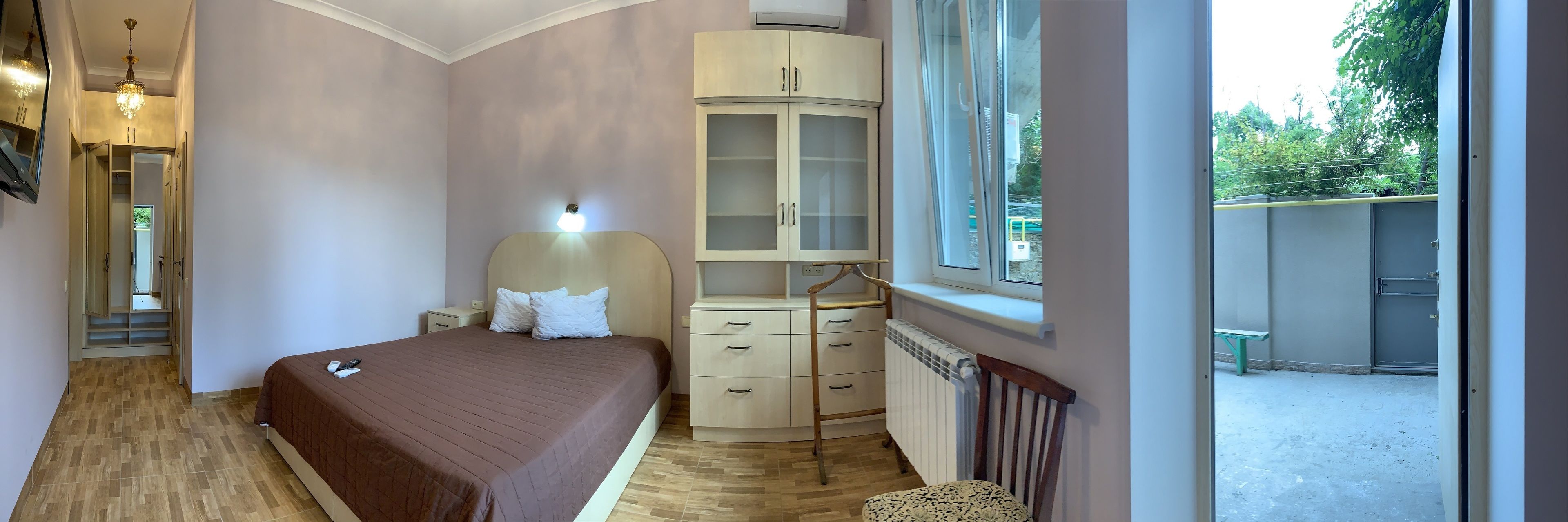 A bedroom with a bed, a wardrobe, a radiator, and a window.