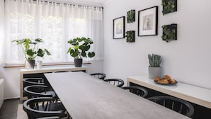 Un comedor moderno con una mesa larga, sillas negras y plantas en macetas.