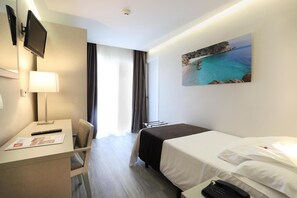 A hotel room with a bed, a desk with a lamp, a TV, a phone, and a painting of a coastal scene. - Helios Benidorm (Benidorm)