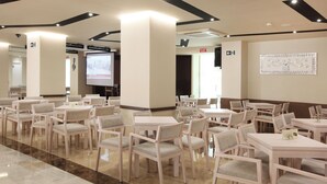 A spacious dining area with multiple tables and chairs, a projection screen, and a wall-mounted decorative piece. - Helios Benidorm (Benidorm)