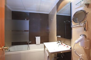 A modern bathroom with a bathtub, a vanity with a mirror, and a hairdryer mounted on the wall. - Helios Benidorm (Benidorm)