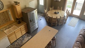 Una cocina compacta con refrigerador, armarios de madera y un comedor con mesa redonda y sillas.