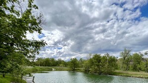 Un entorno frente al lago con una zona de arena, varias sillas de descanso y una mesa de picnic.