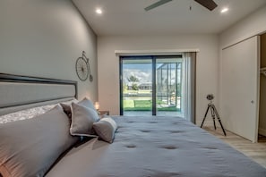 A bedroom with a large bed, a bicycle wall decoration, and a sliding glass door leading to a balcony. - Villa Southbreeze by Vacationhit (Cape Coral)