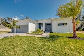 A modern two-story house with a garage, a well-maintained lawn, and a palm tree. - Villa Southbreeze by Vacationhit (Cape Coral)
