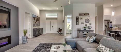 Ein modernes Wohnzimmer mit einem großen grauen Sofa, einem weißen Couchtisch und einem Deckenventilator.